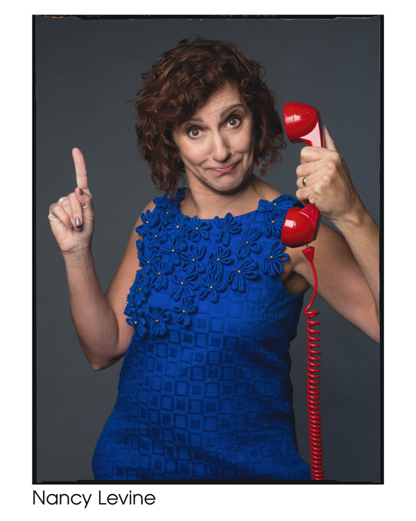 Nancy Levine in a blue floral dress holding a red phone